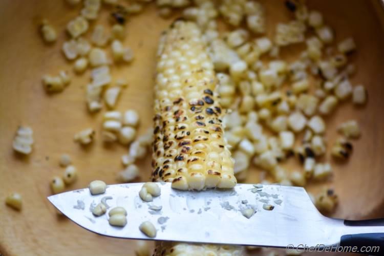 Removing kernels of roasted corn with knife for Street Corn Salad