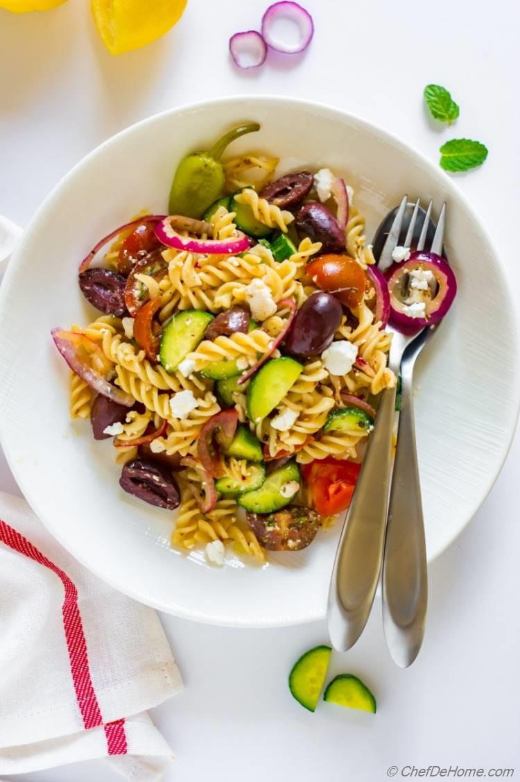 Greek salad with fussili pasta red onion olives and cucumber