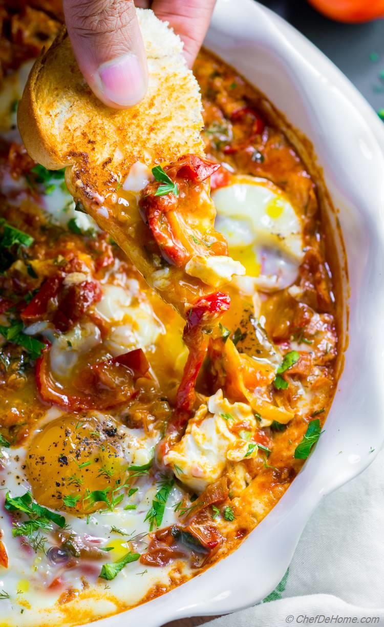 Shakshuka with bread dipped in egg yolk